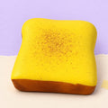 Dikke toast squishy – Dikke toast squishy, kussentje van 11 cm (Botergeel), productfoto op pastelpapier
