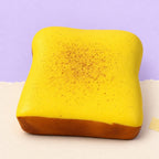 Dikke toast squishy – Dikke toast squishy, kussentje van 11 cm (Botergeel), productfoto op pastelpapier