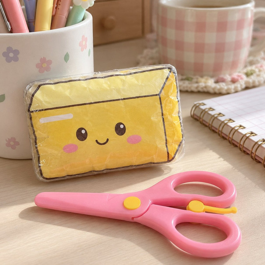 Tijeras de manualidades para niños en rosa junto a una mantequilla de papel