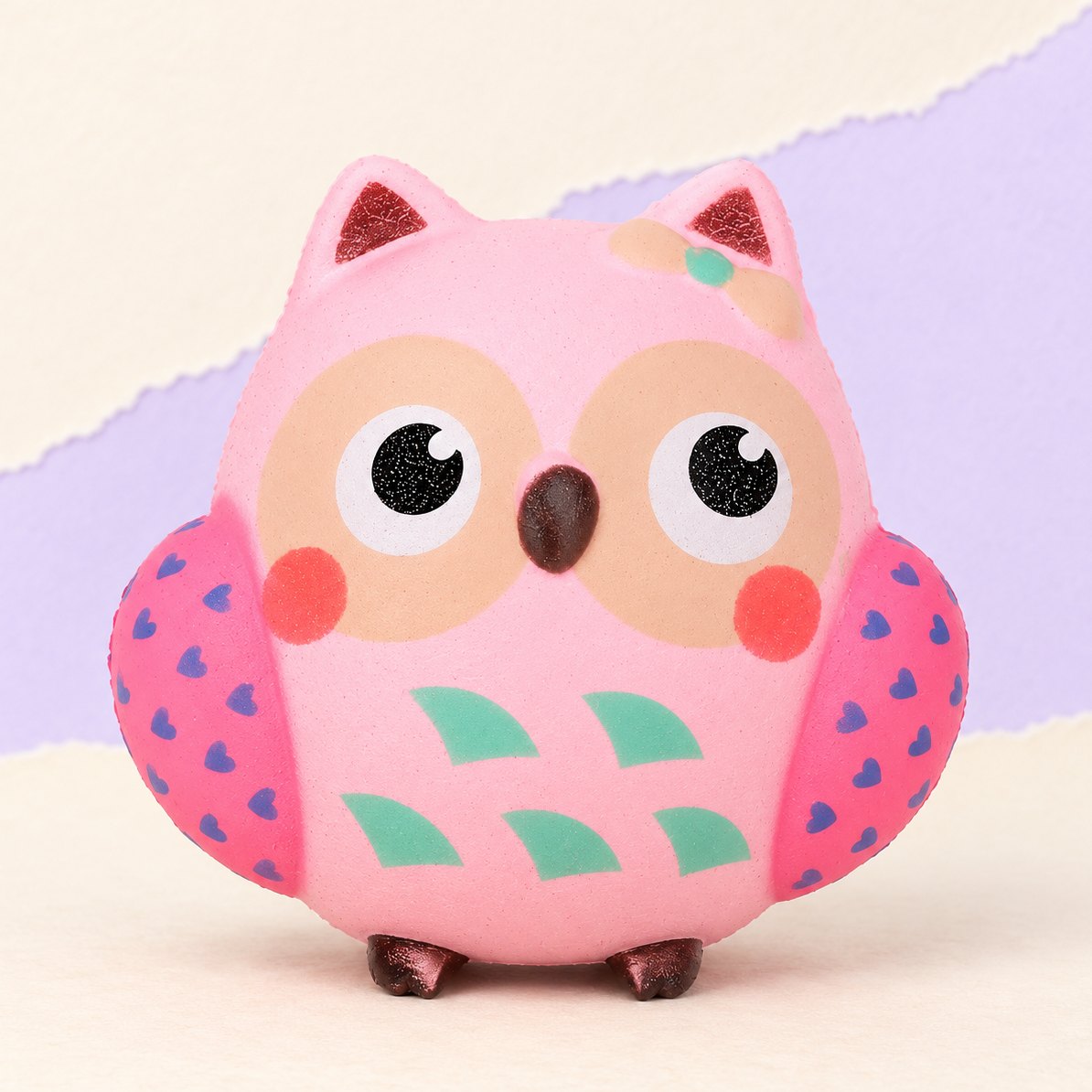 Lyserød ugle-squishy, produktfoto på pastelfarvet papir