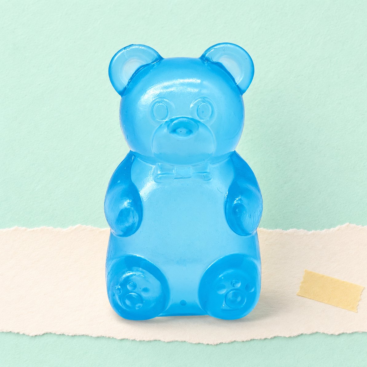 Blå vingummibamse-squishy, produktfoto på pastelfarvet papir