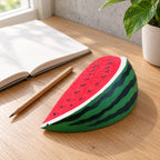 Watermelon Squishy, Slow Rising PU, on a desk with a notebook and pencil